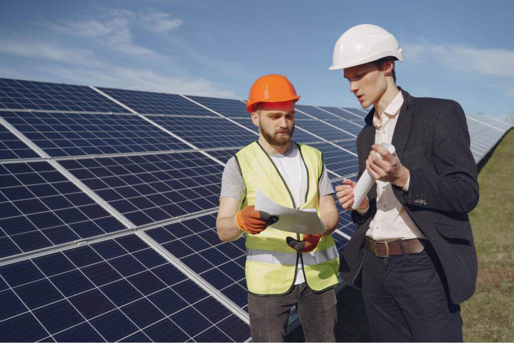 Due professionisti discutono le pratiche del kit solare Easy Solar davanti ai pannelli solari.