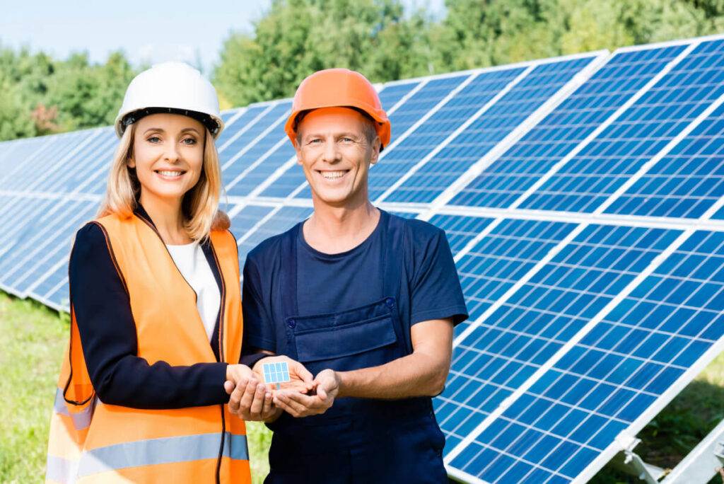 Due ingegneri con un Easy Solar Kit e una calcolatrice solare davanti ai pannelli solari.