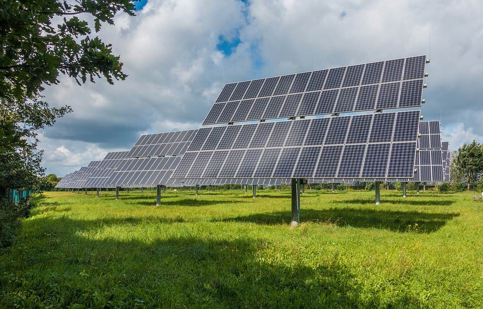 Solar panels array with a Micro Inverter in a green field under a partly cloudy sky.