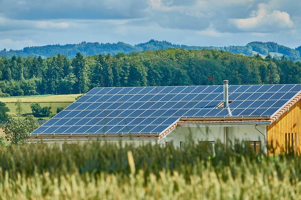 Solar panels installed on the roof of a house in a rural setting, featuring an efficient Micro Inverter system.