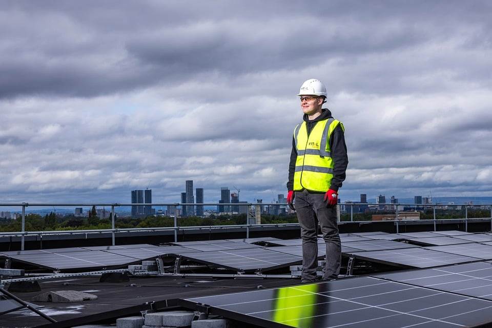 Engineer inspecting solar panels with a Micro Inverter on a rooftop with a city skyline in the background.