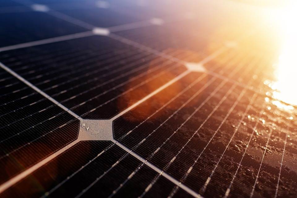 Close-up of a solar panel with sunlight reflecting off its surface, connected to a Micro Inverter.