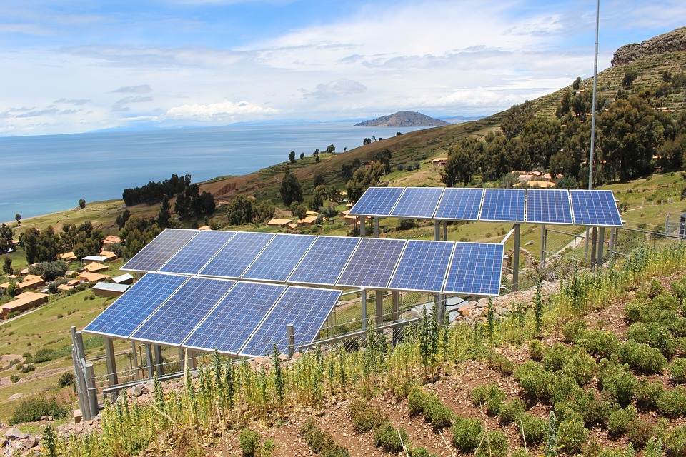 Solar panels, including an Easy Solar Kit, installed on a hillside with a view of a large lake in the background.