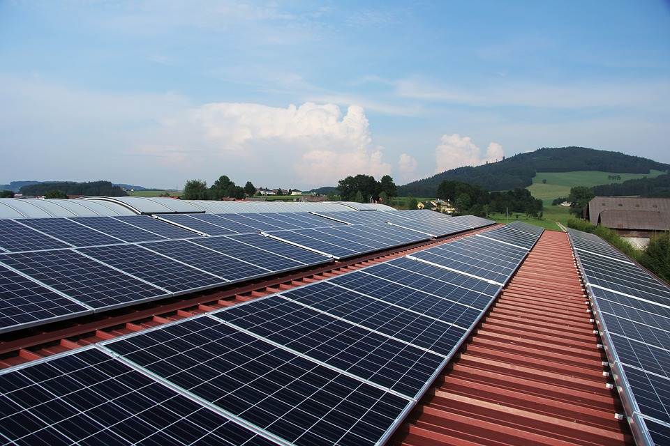 A solar panel installation with an Easy Solar Kit on a building, with rolling hills and a blue sky in the background.