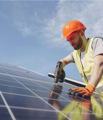 Worker installing solar panels with an Easy Solar Kit on a bright day.